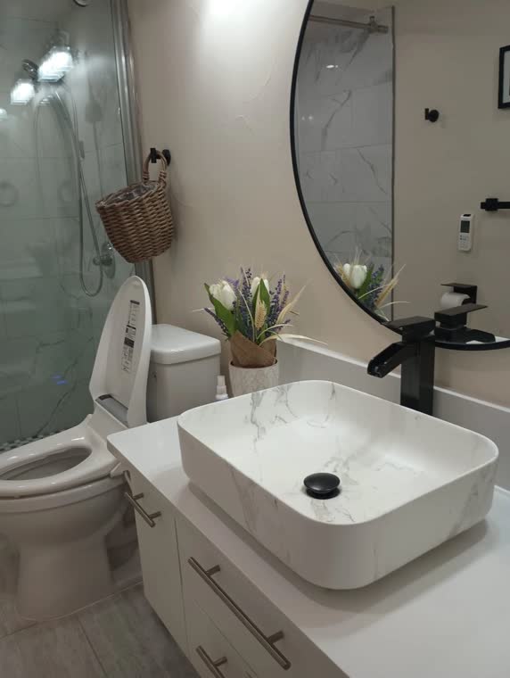 Bathroom with a white vessel sink, round mirror and toilet.