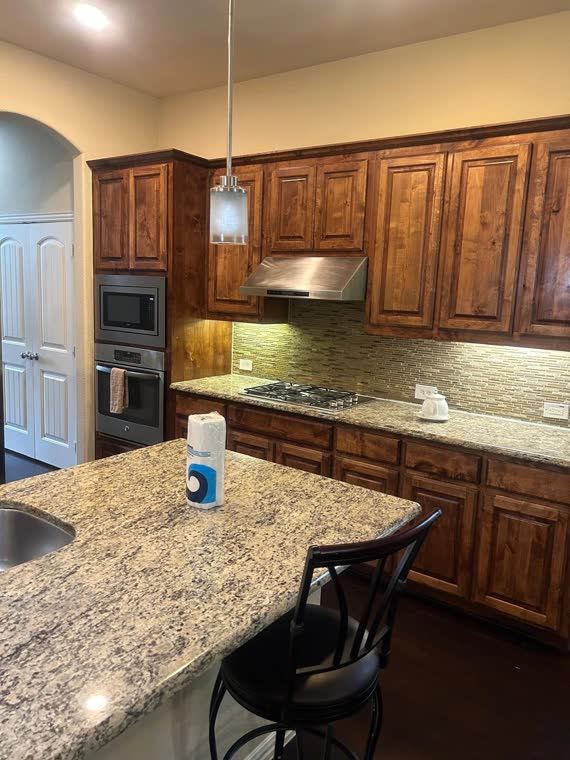 Kitchen with wood cabinets, a granite island and a bar stool.